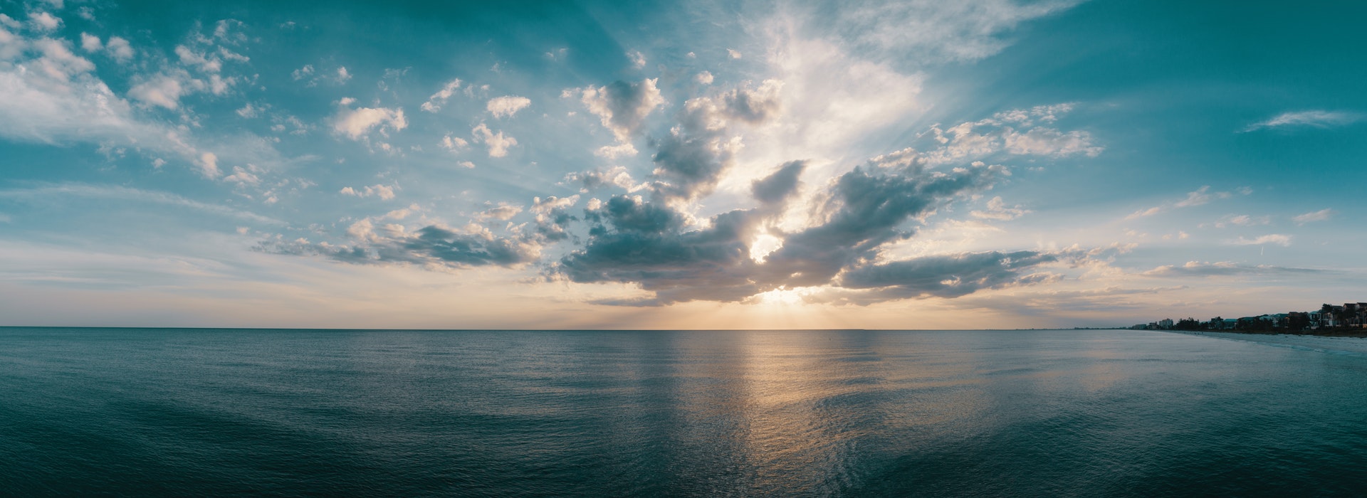 Nuages cotonneux au-dessus d’un océan bleu foncé au coucher du soleil.