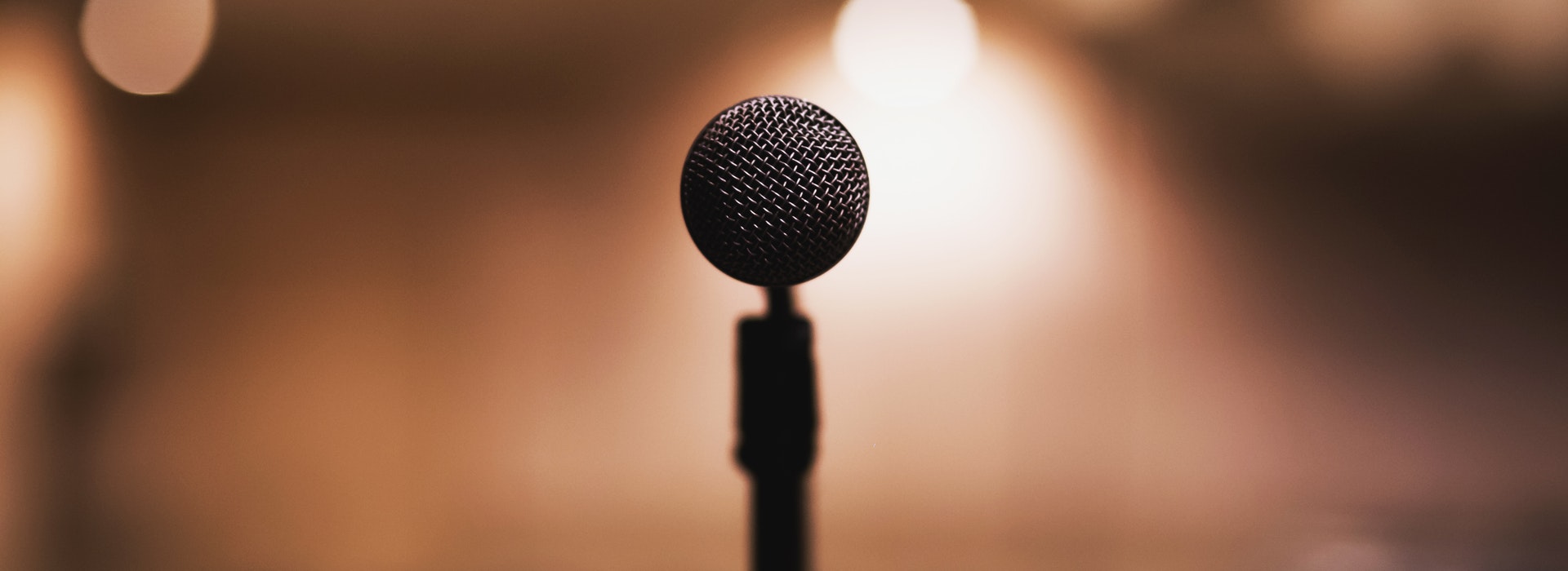 Closeup photo of a microphone against a blurry brown background