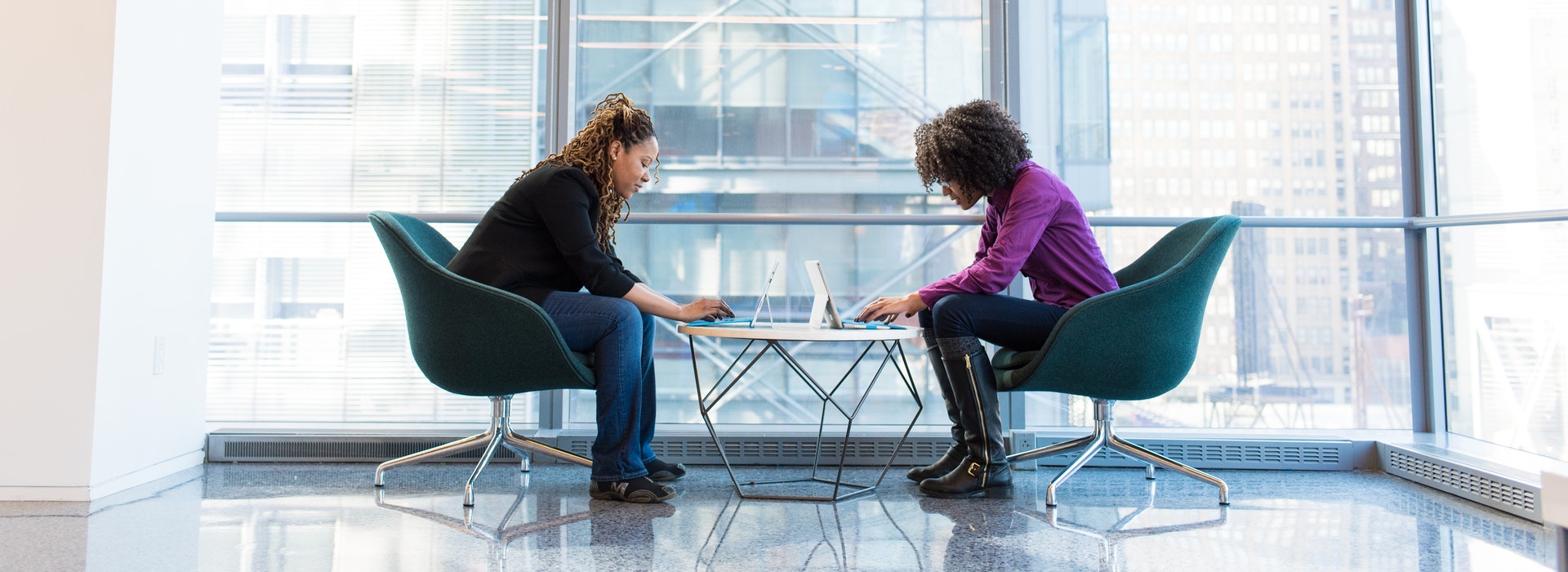 Deux femmes sont assises en face l'une de l'autre, travaillant sur des ordinateurs portables